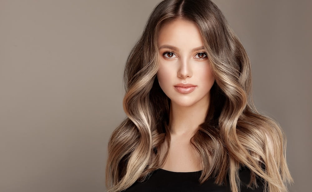 A woman with long, wavy hair and flawless skin looks confidently into the camera, exuding elegance and poise - Walnut Creek Aesthetics A woman with long, wavy hair and flawless skin looks confidently into the camera, exuding elegance and poise - Walnut Creek Aesthetics